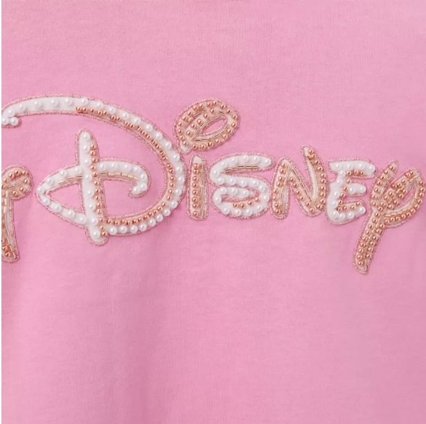 Disney logo with pearl embellishments on pink fabric.