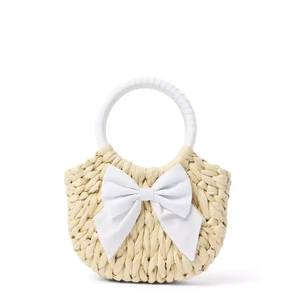 Stylish woven straw handbag with white bow and handle, perfect for Easter and spring outings.