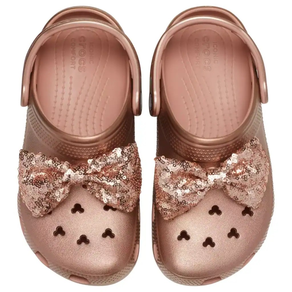 Pink Disney Crocs with sequin bow, heart cutouts, perfect for kids' Disney fashion.