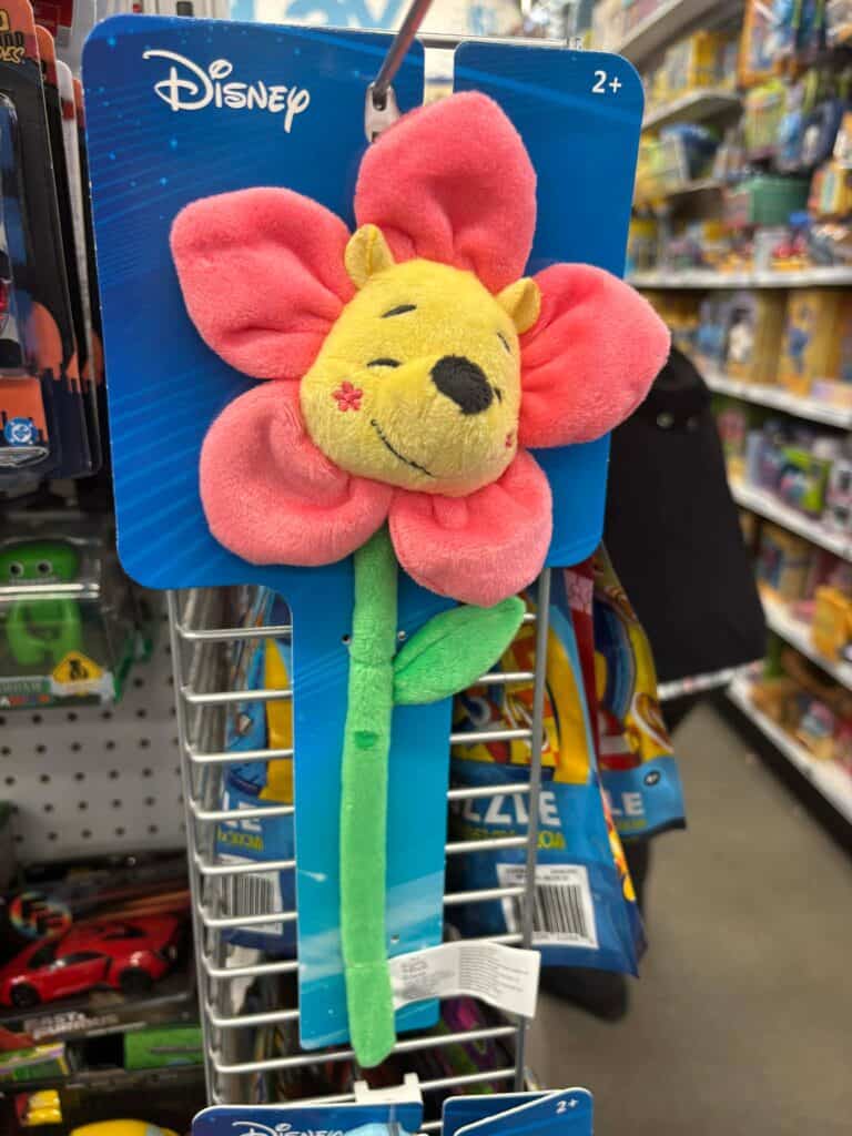 Soft flower-shaped plush toy with a smiling Winnie the Pooh face and pink petals.
