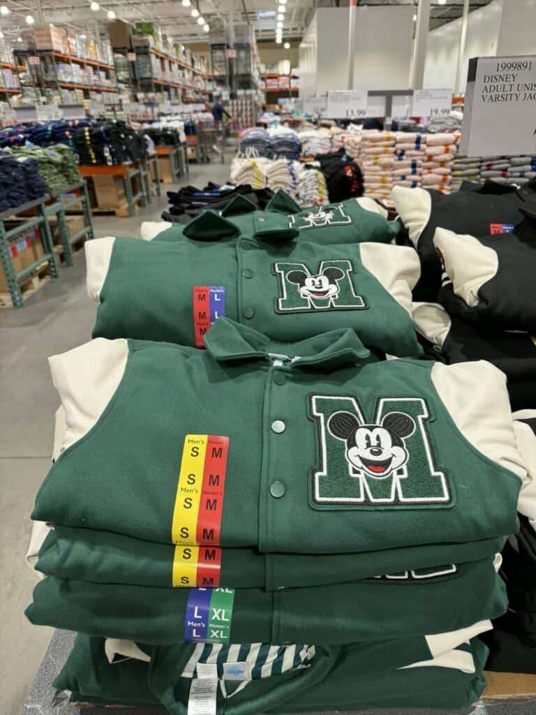 Green Mickey Mouse varsity jacket with embroidered logo, displayed in store.