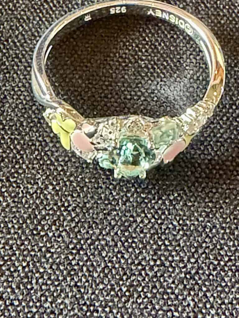 Elegant Disney-themed ring with a green gemstone and floral accents.