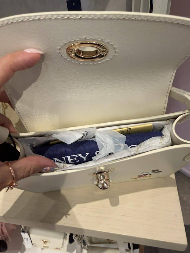 Neutral Mickey Mouse Dooney & Bourke crossbody bag with gold hardware.