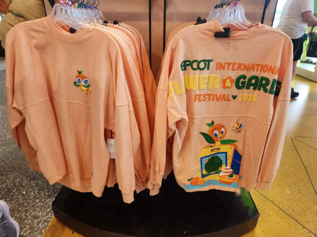 Peach-colored sweatshirts featuring Disney Flower & Garden Festival 2023 design.