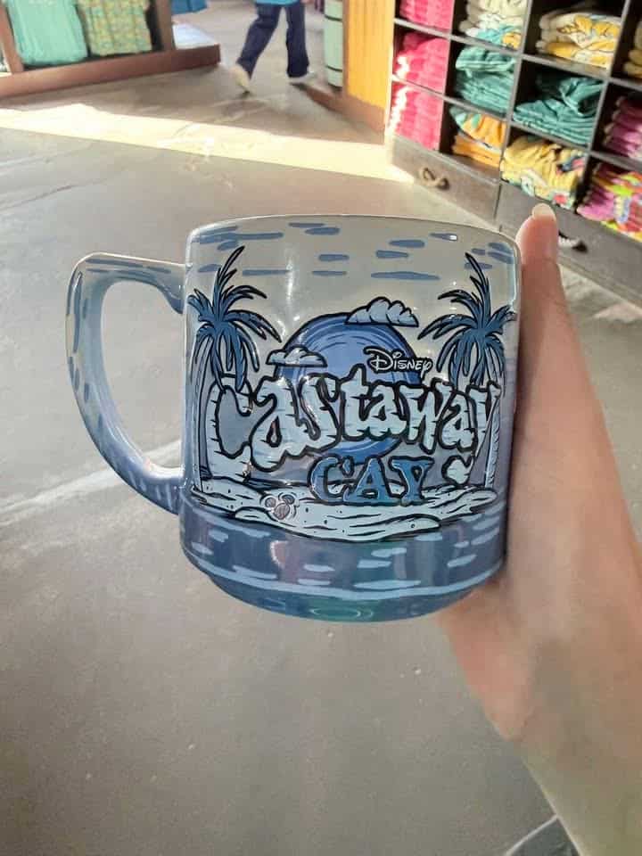 Disney-themed beach mug with palm trees and ocean scene.