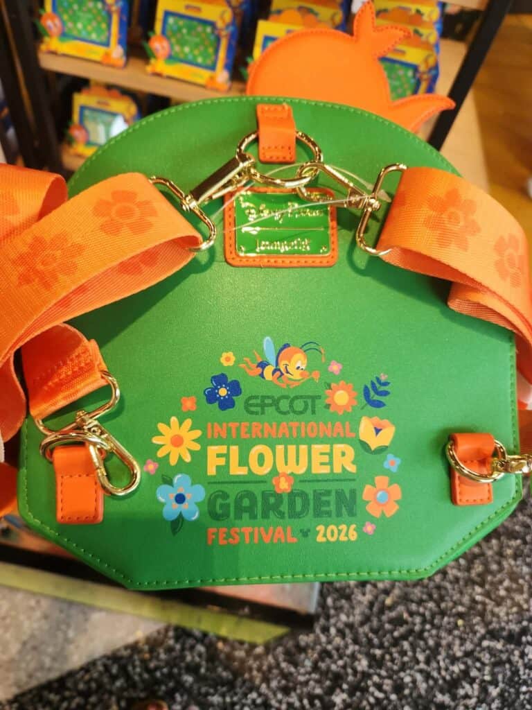 Colorful Disney-themed handbag with floral and garden motifs.