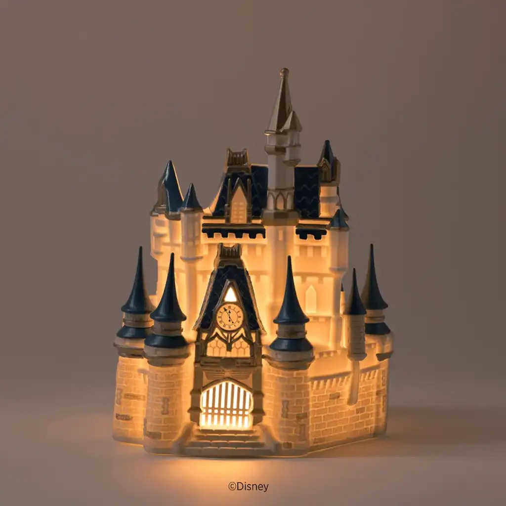 Illuminated Disney castle model with glowing windows and towers.
