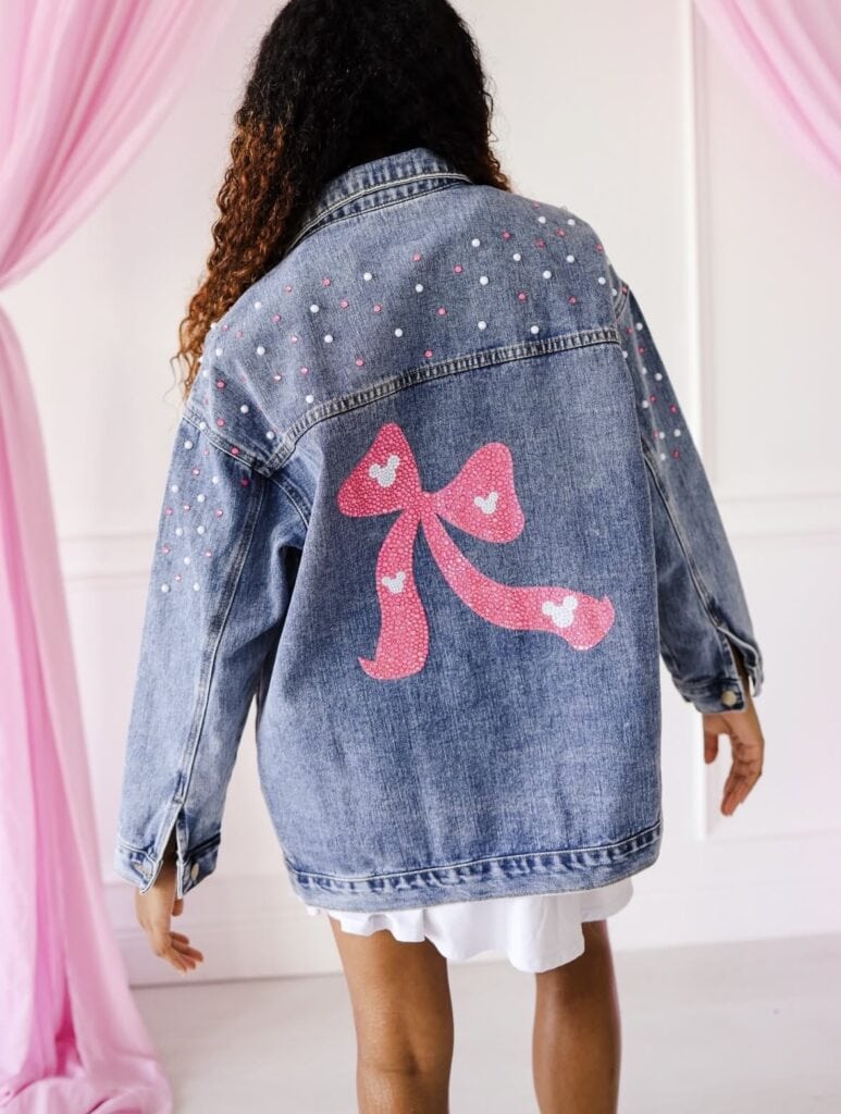 Disney fashion jacket with pink bow and decorative accents for a playful look.