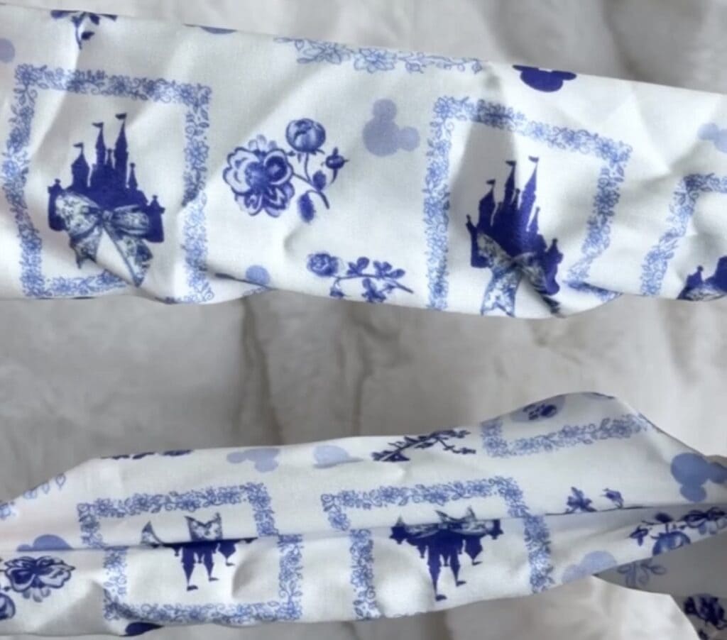 Blue floral fabric with Disney castle and floral motifs, perfect for crafting or sewing projects.