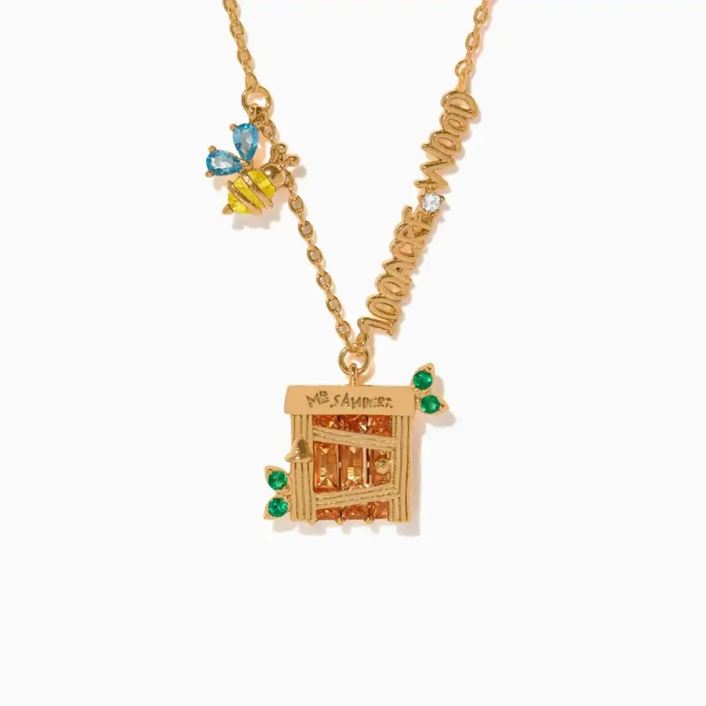 Gold necklace with Disney-inspired charm featuring a small house and colorful accents.