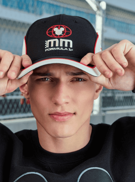 Young man wearing a Formula 1 Mickey Mouse cap outdoors.