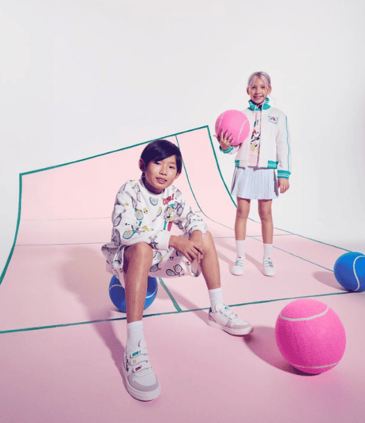 Kids wearing Disney x Marc Jacobs tennis outfits with colorful balls on a pastel court.