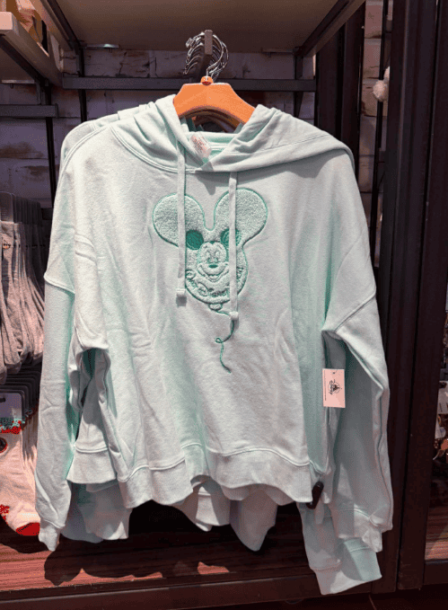 Light mint green Mickey Mouse hoodie with drawstrings, displayed on a hanger.