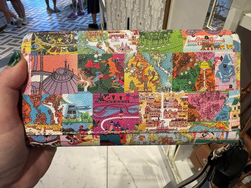 Colorful Disney-inspired patchwork wallet with vibrant, detailed designs of iconic attractions and c.