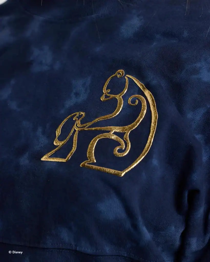 Embroidered Disney princess logo on navy fabric, showcasing elegant gold stitching.