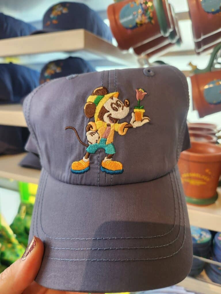 Embroidered Mickey Mouse wearing a hat, holding a flower pot, on a gray baseball cap.