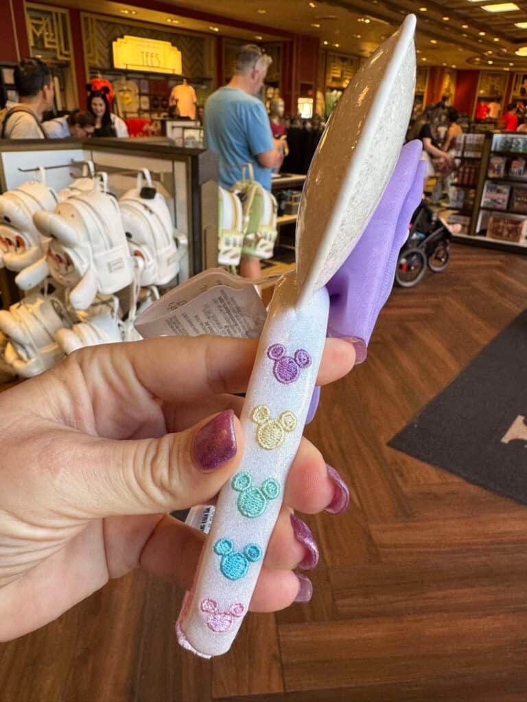 Hand holding Minnie Mouse-themed ice cream bar at Disney store.