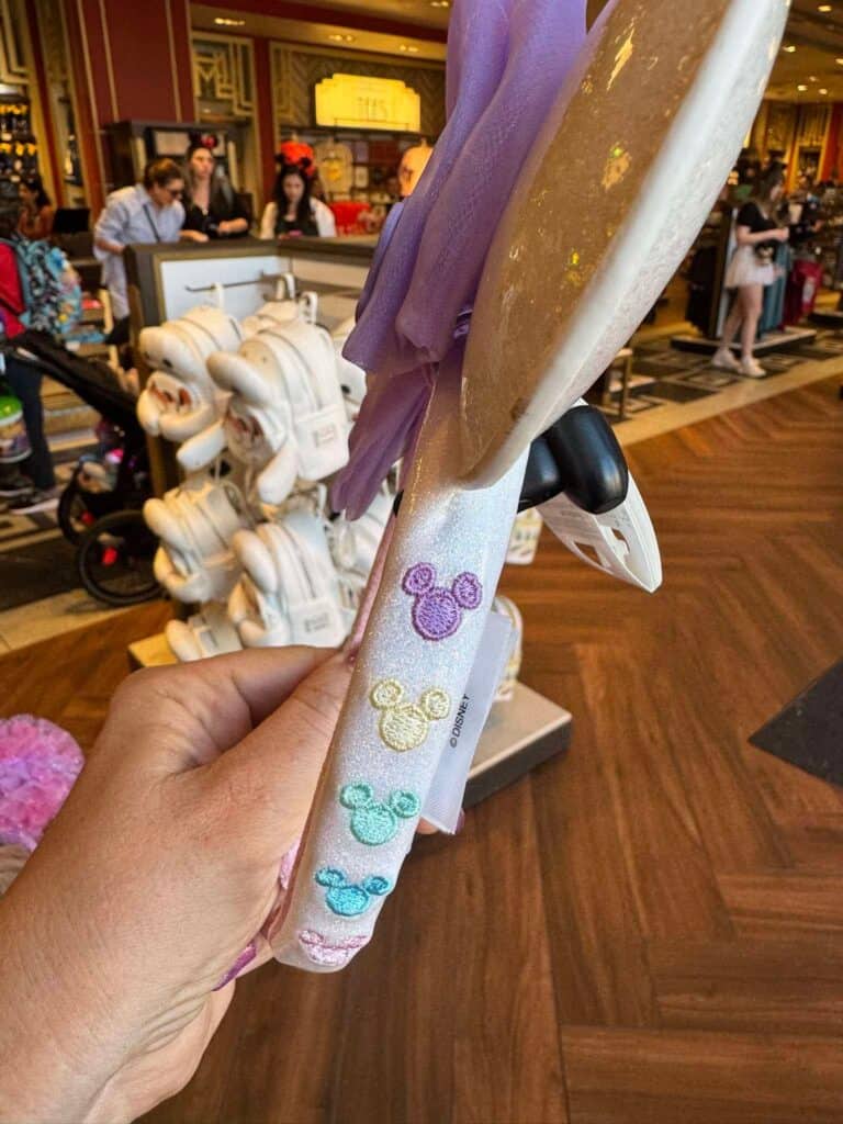 Colorful Disney princess umbrella with Mickey Mouse handle details in a Disney store.