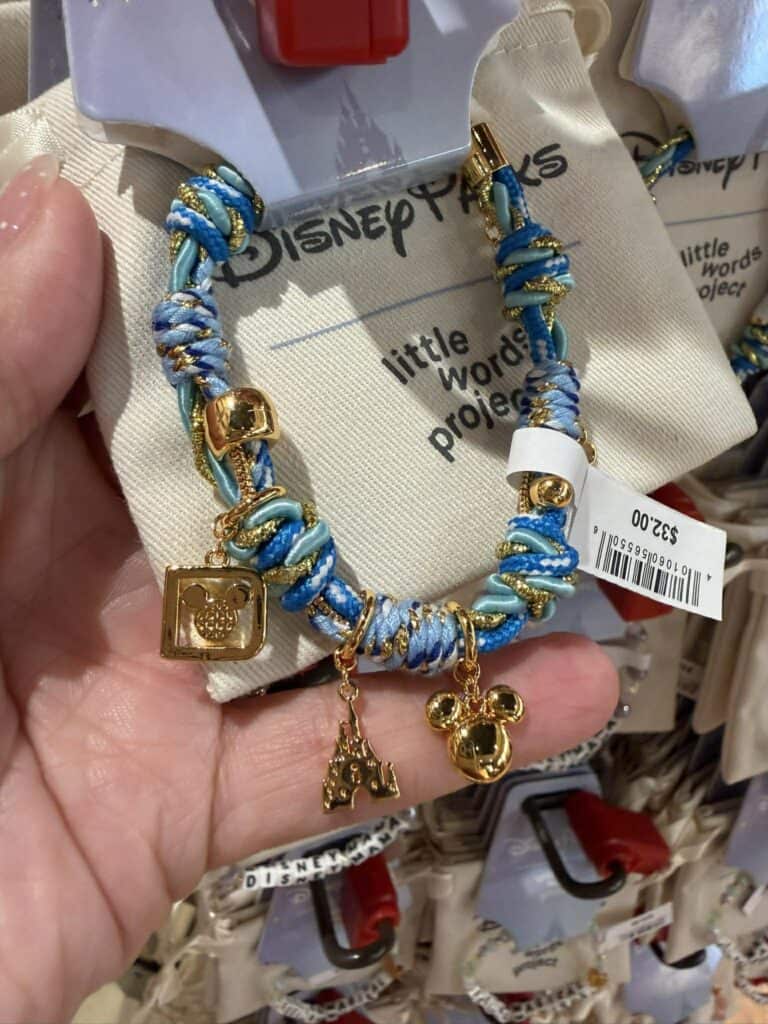 Bracelet featuring blue and white threads with gold charms, debuting at Walt Disney World.