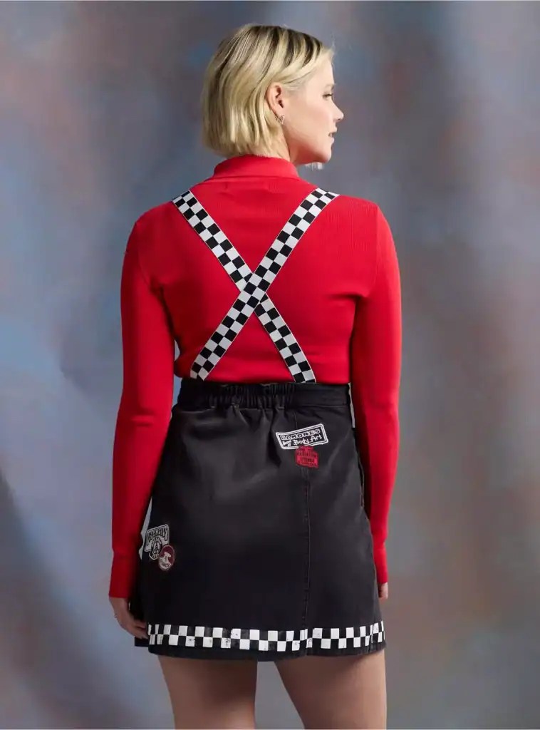 Woman in red top and checkered skirt with suspenders, back view.