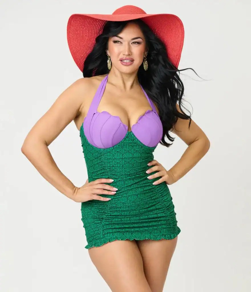 Woman in Disney-inspired mermaid costume with red hat and purple top, green skirt.