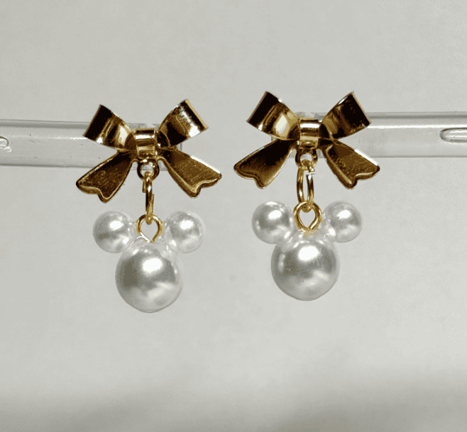 Gold bow earrings with pearl charms, ideal for Disney-themed jewelry and fashion statements.