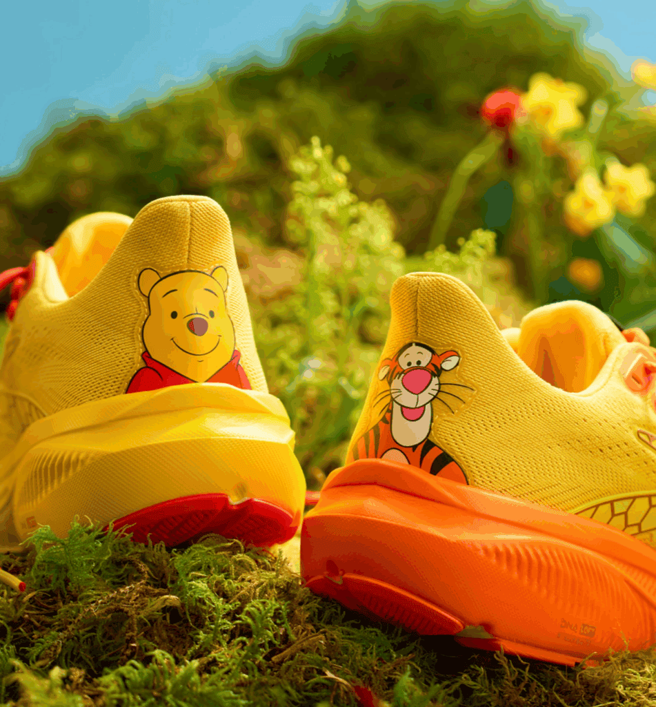 Bright yellow Winnie the Pooh and orange Tigger themed Disney shoes outdoors.