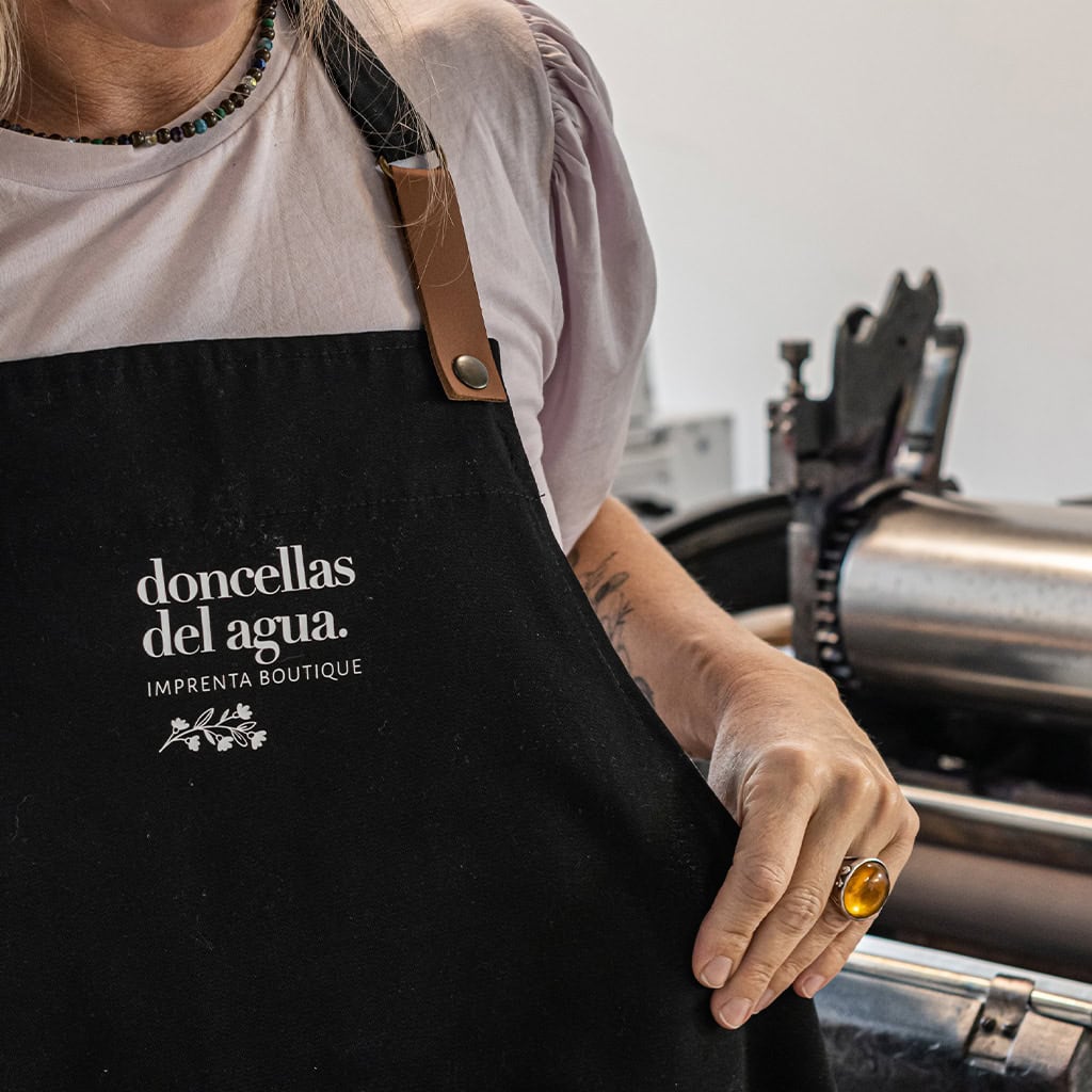 Personal de Doncellas del Agua en la producción de papelería artesanal, vistiendo delantales personalizados en letterpress, en un taller dedicado a la impresión boutique de alta calidad en Argentina.