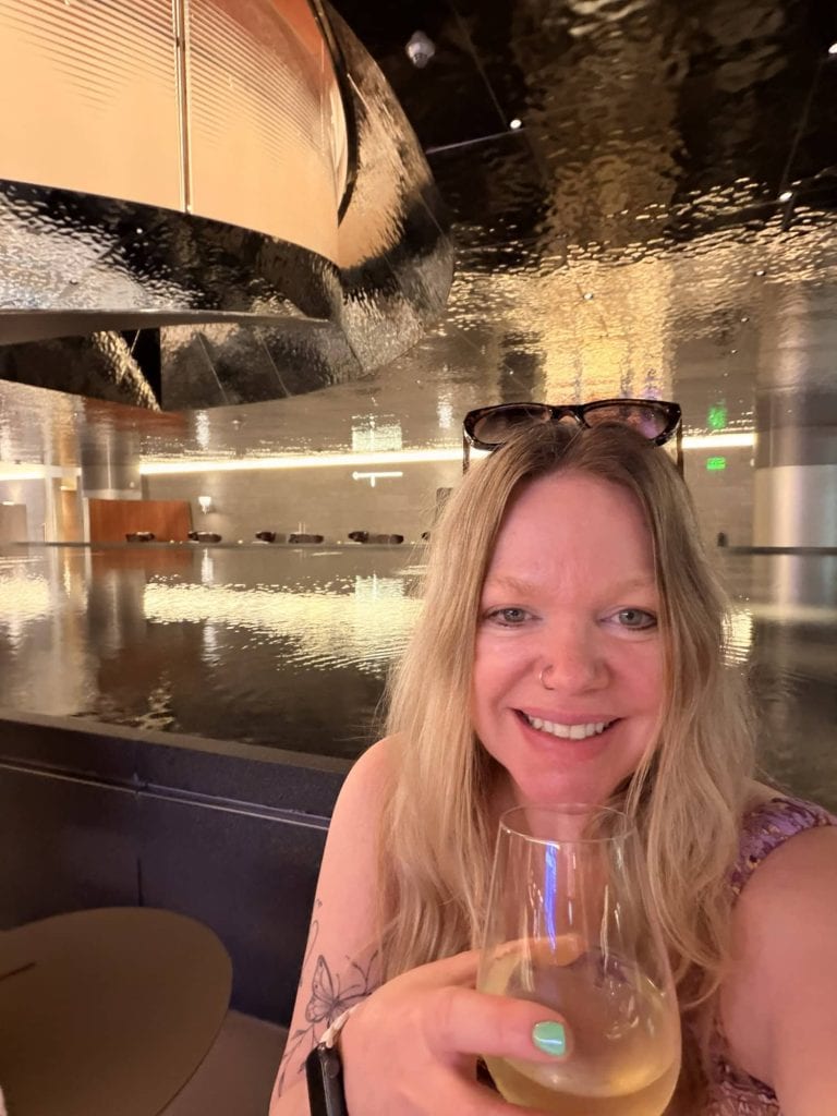 Woman enjoying wine at sunset marina view.