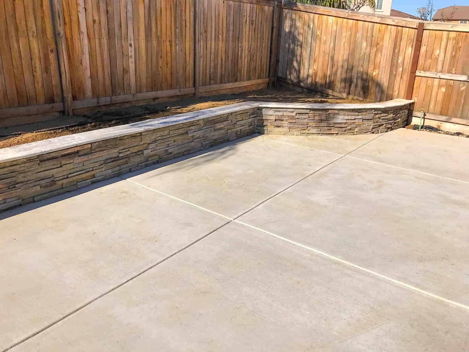 A newly installed concrete patio with an elegant stacked stone retaining wall in Davis