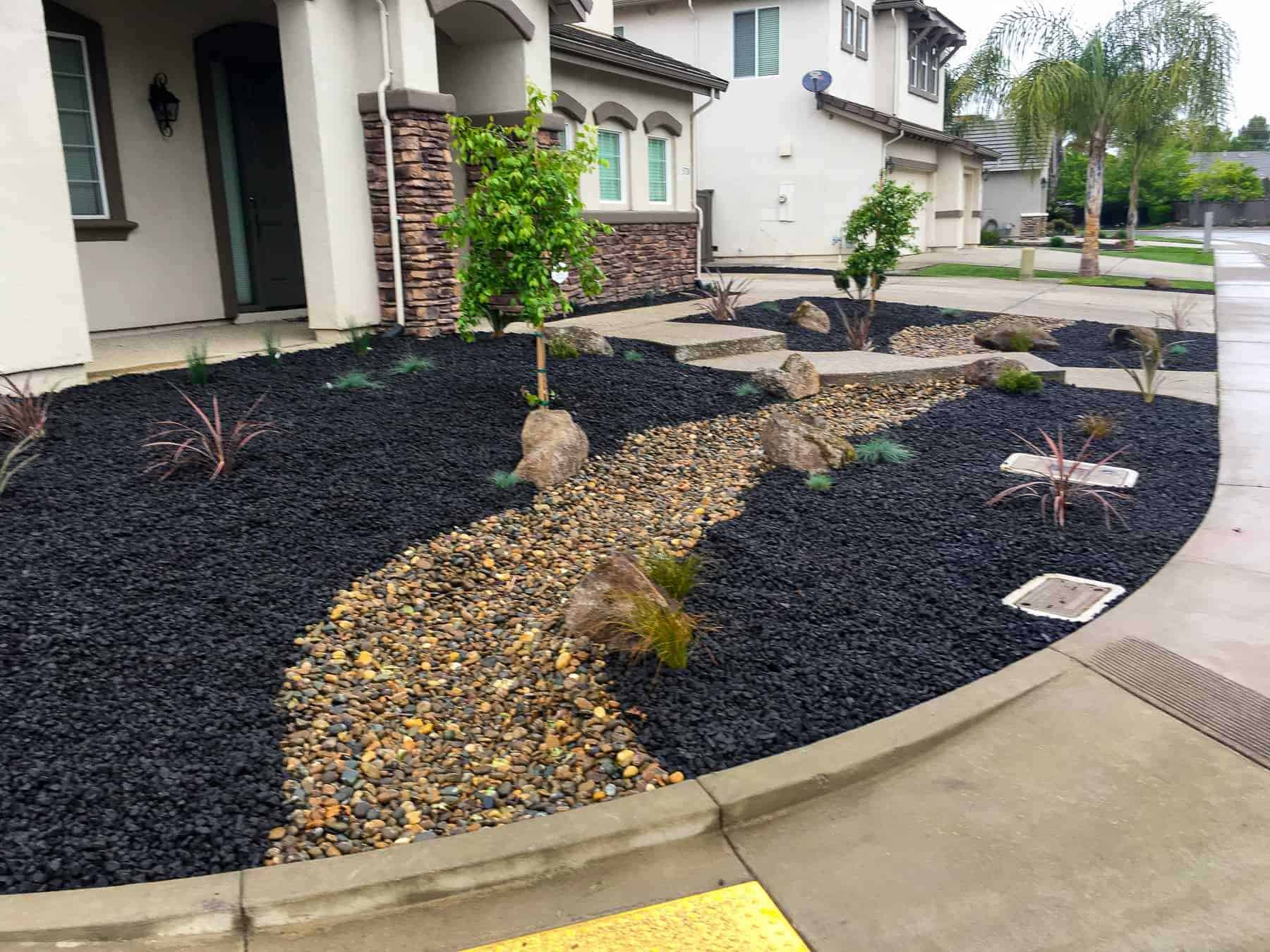 Front yard landscaping with bark, plants, and rock pathway in LINCOLN