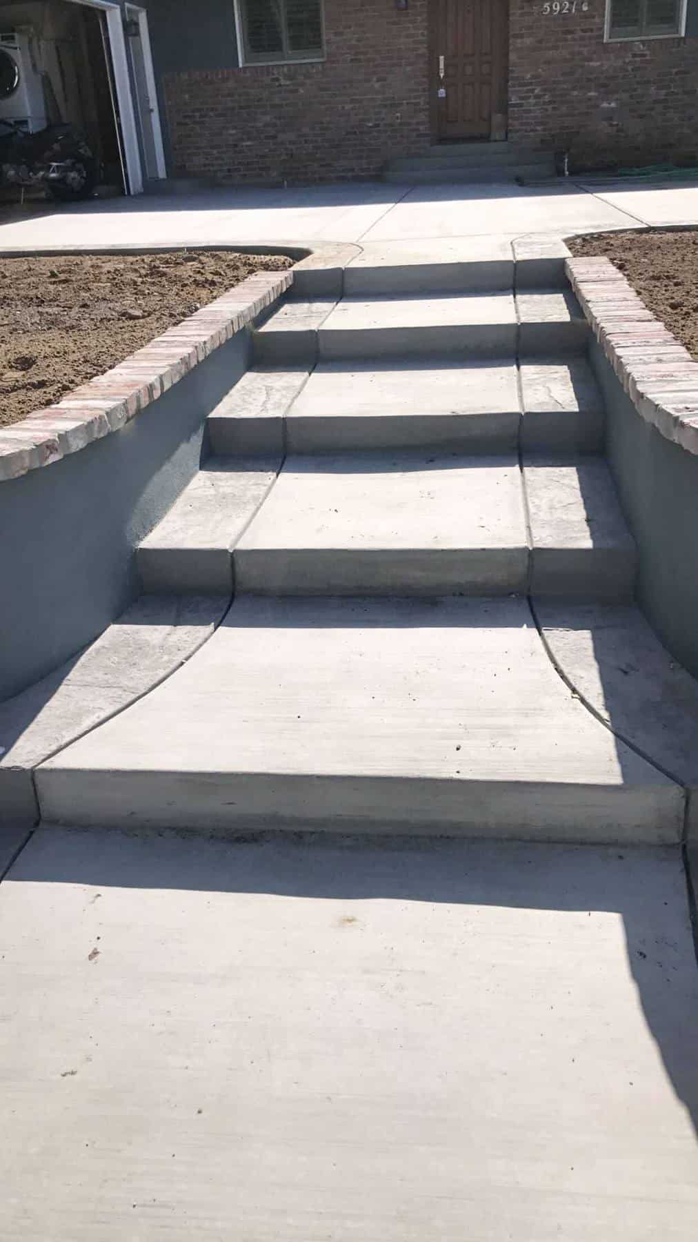 Newly installed concrete steps and an entry walkway in PLYMOUTH, flanked by low brick retaining walls