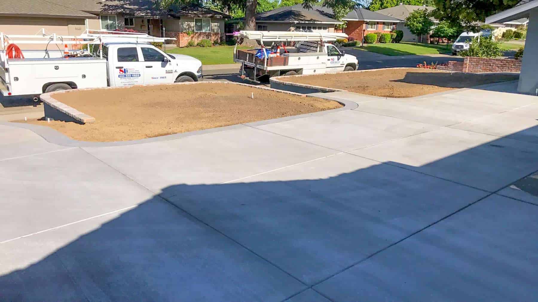A newly installed concrete driveway with decorative brick-edged planting beds at a home in RANCHO MURIETA
