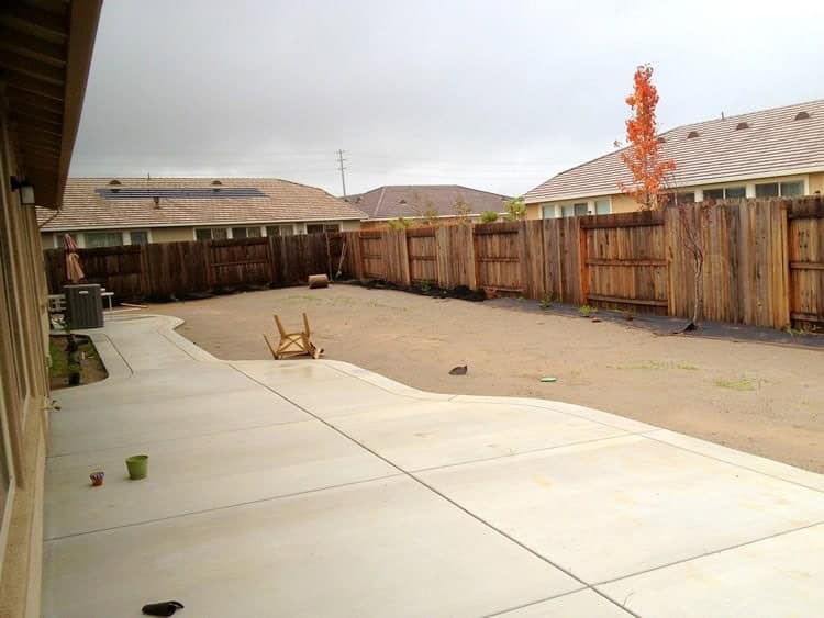 A newly installed, curved concrete patio provides a functional outdoor living space in a Rio Vista backyard