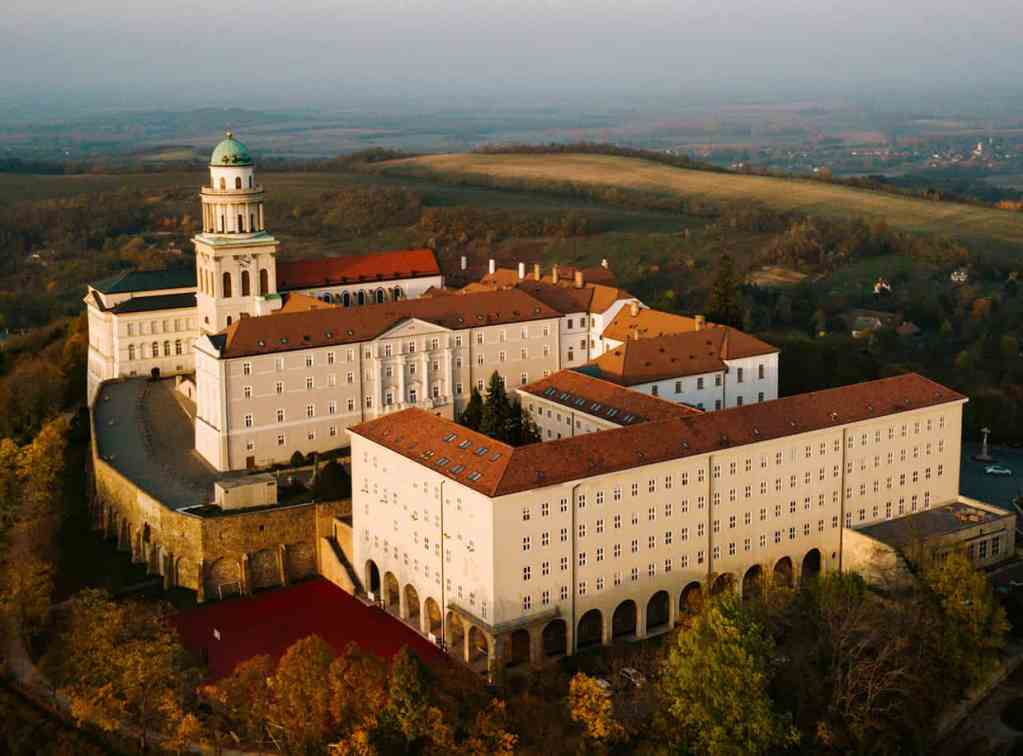 Aerial view of Heiligenkreuz Abbey castle in Austria with rolling countryside, representing premium