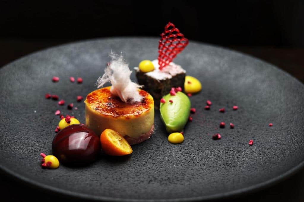 Gourmet fine dining plated dessert with fresh fruits and chocolate garnish