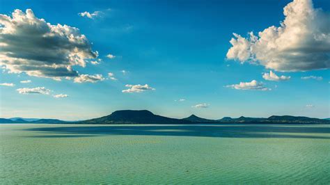 Scenic turquoise lake landscape with mountains under blue sky with white clouds - Hungary travel des