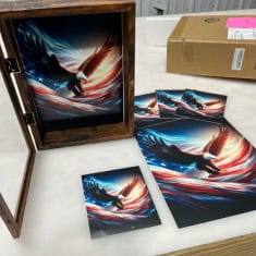 Framed artwork of a dynamic American flag waving in the wind, displayed on a wall at I39 Supply trailer dealership, showcasing quality and patriotic pride.