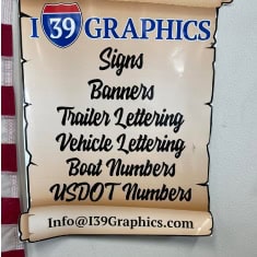 Sign at I39 Supply trailer dealership showcasing services including banners, trailer lettering, vehicle lettering, boat numbers, and USDOT numbers.
