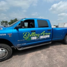 Blue pickup truck with Rolling Acres Farm & Livestock logo, showcasing a trailer dealership vehicle at I39 Supply. Perfect for farm and livestock trailer sales and service.