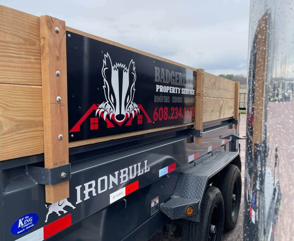 Trailer with custom signage for I39 Supply, featuring a bold logo and contact information, attached to a black utility trailer with wooden side panels.