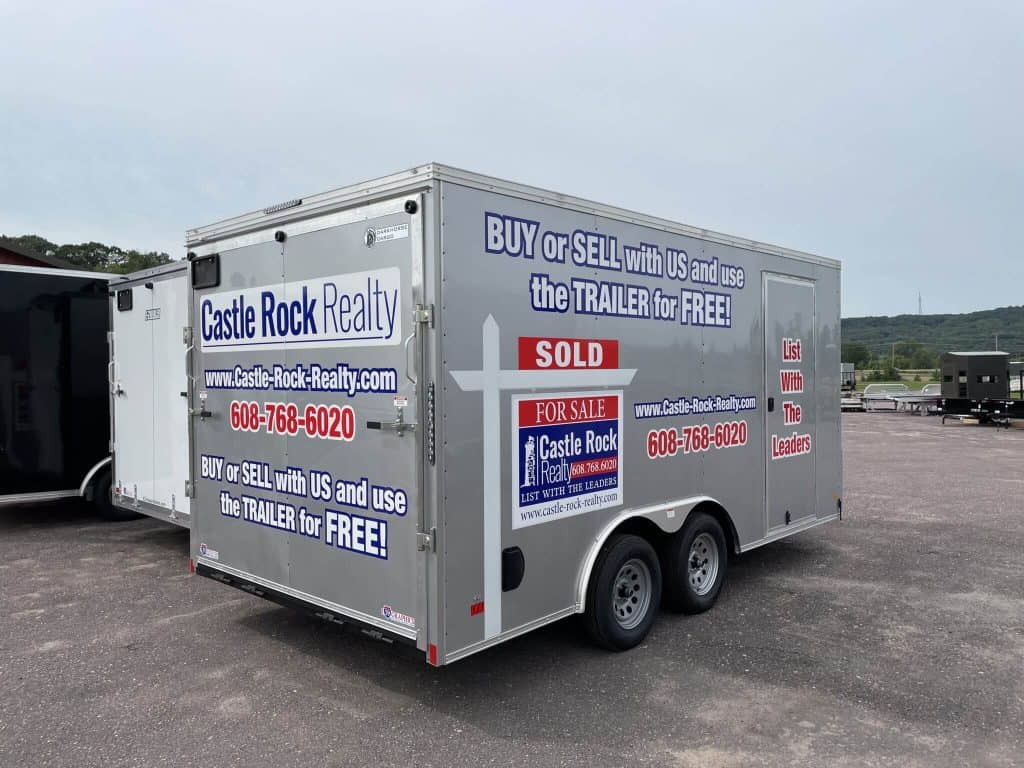 Mobile trailer dealership trailer with Castle Rock Realty branding, offering buy, sell, and trade services for trailers in a spacious outdoor lot.
