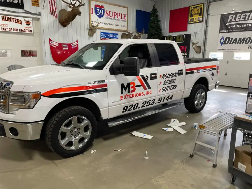 White work truck with I39 Supply trailer dealership graphics, parked inside a service garage with tools and signage in the background.