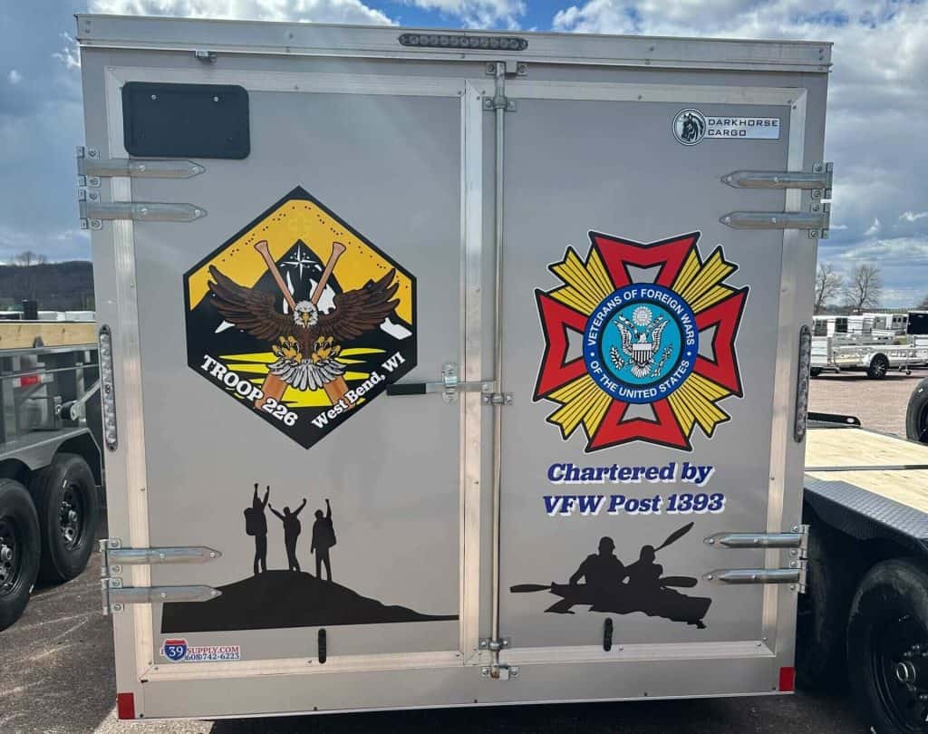 White cargo trailer featuring Troop 228 West Bend WI emblem, military insignia, and veteran symbols, used for community and veteran support events.