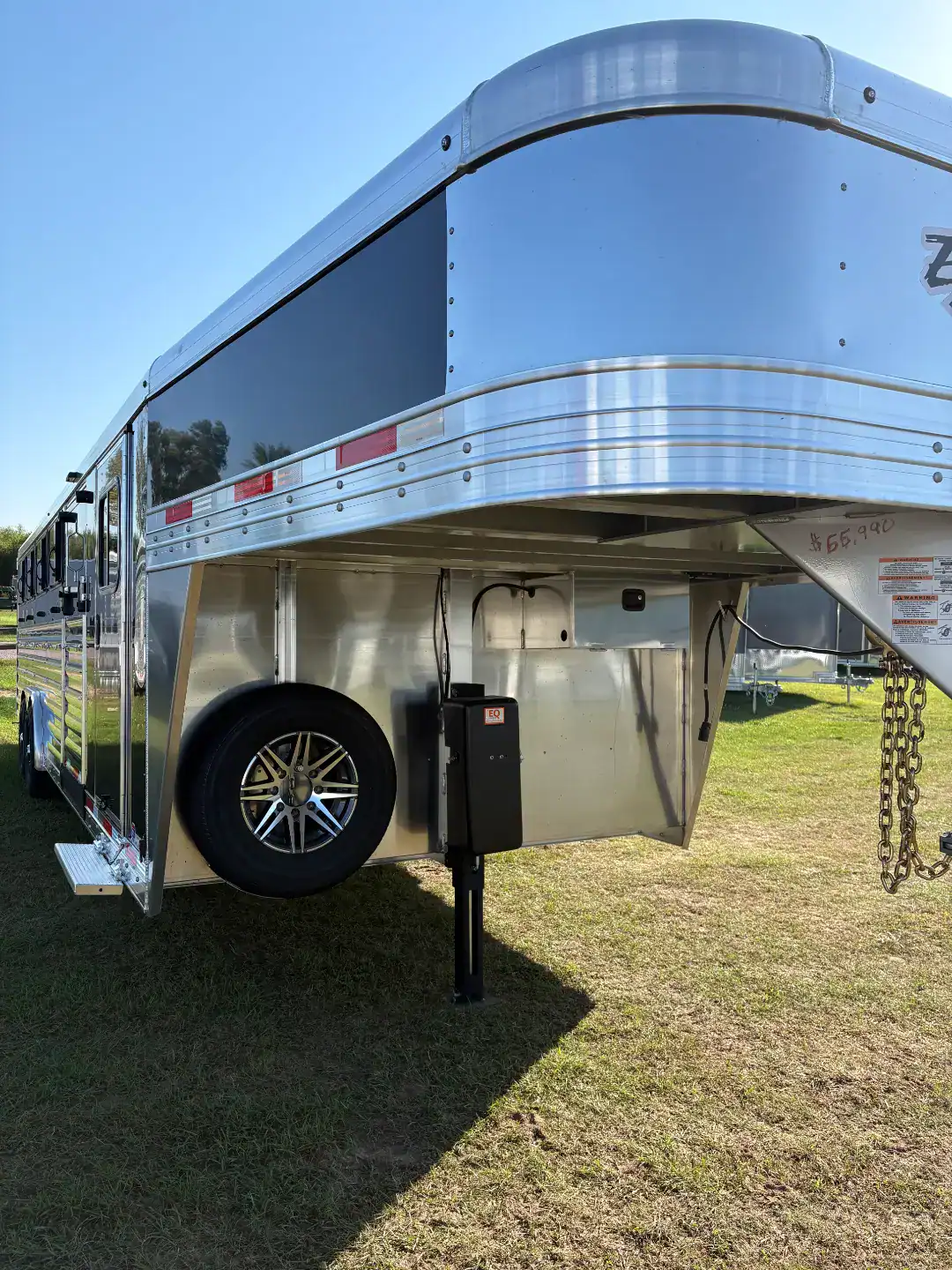 Aluminum livestock trailer with gooseneck design, rear and side ramps, and tack room for efficient animal transport. Perfect for professional farms and ranches.