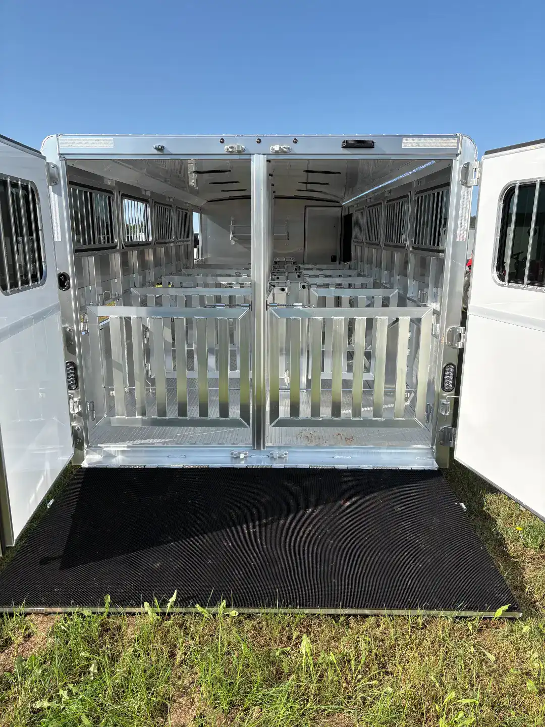 Aluminum livestock trailer with rear and side ramps, tack room, ideal for transporting animals securely. Features durable construction and spacious interior for efficient livestock management.