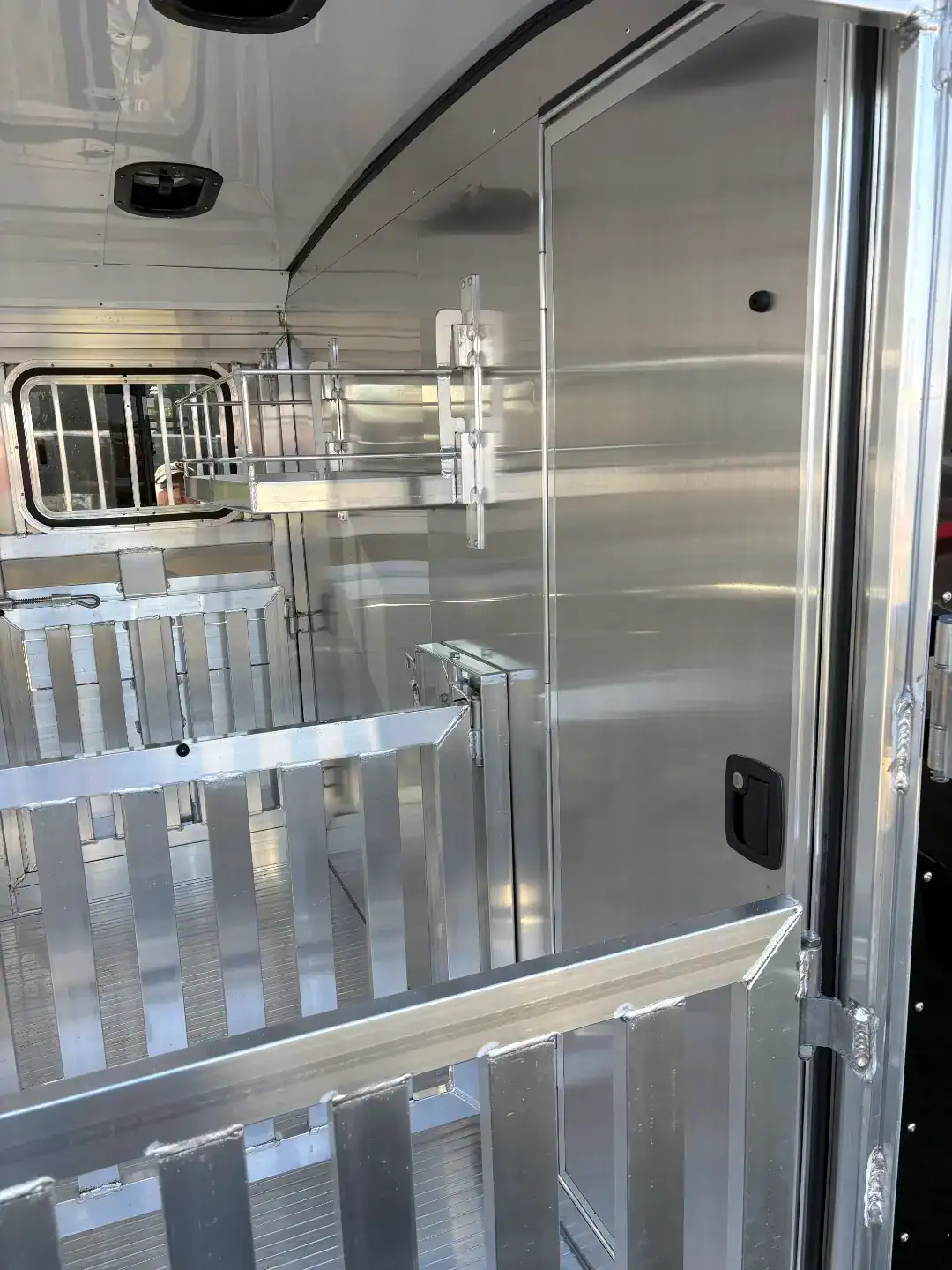 High-quality aluminum livestock trailer with rear and side ramps, tack room, and gooseneck design for efficient animal transport.