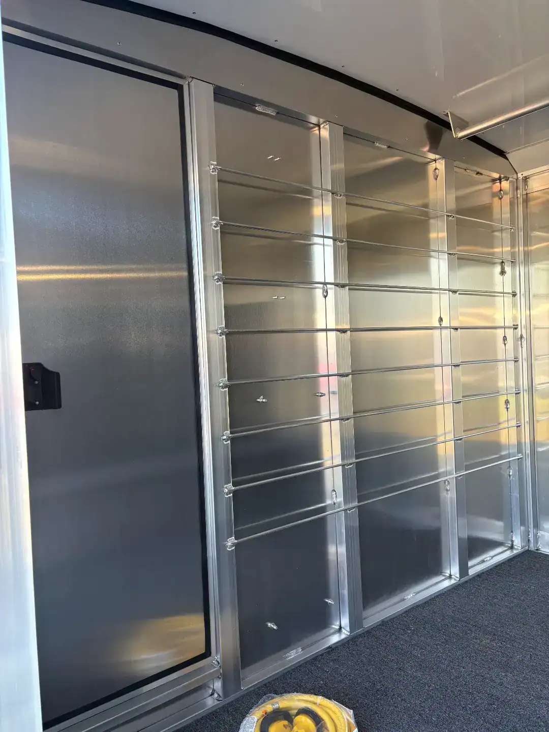 Aluminum livestock trailer with gooseneck design, rear and side ramps, and a spacious tack room, ideal for transporting animals securely and comfortably.