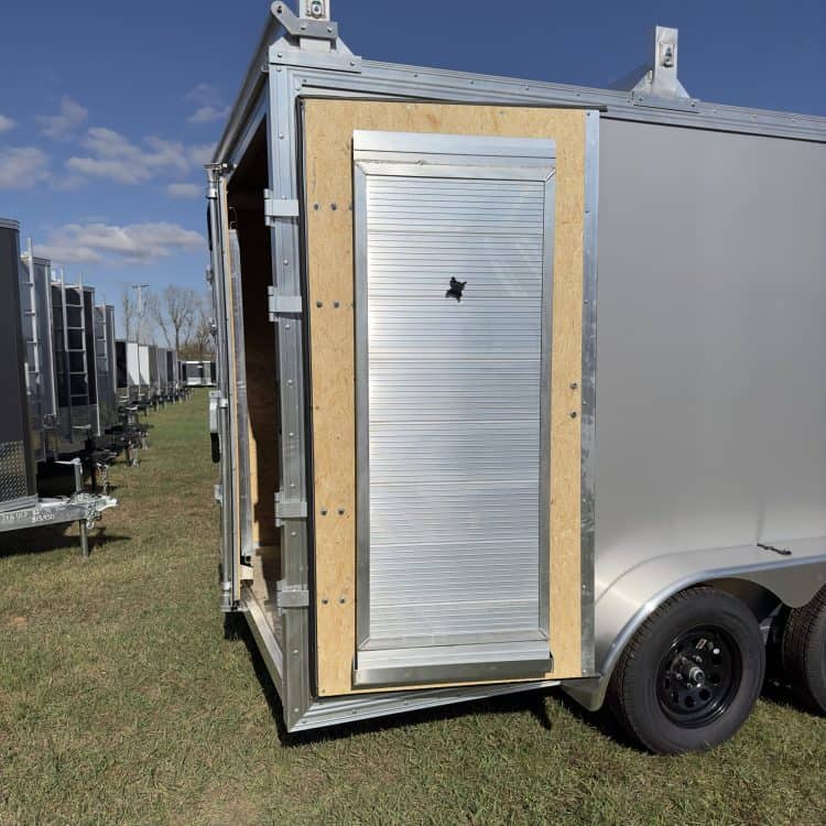 A sturdy, silver-colored trailer featuring a secure roll-up door, perfect for commercial or personal use at I39 Supply Trailer Dealership.