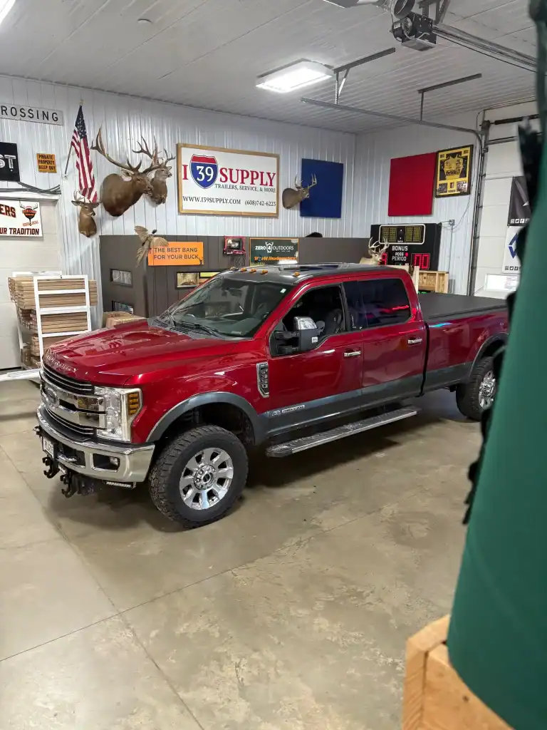 Used red pickup truck at I39 Supply trailer dealership with vintage signs and decor in the background.